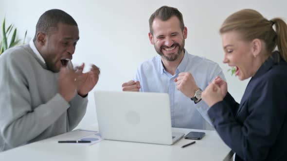 Mixed Race Business People Celebrating Success While Using Laptop in Office