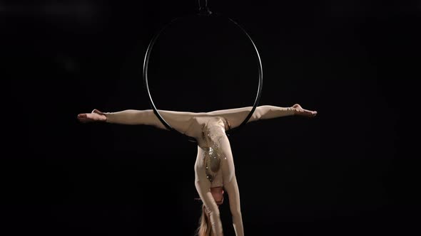 Wide Shot Young Skilled Aerial Gymnast Training Gazelle Trick on Air Hoop at Black Background