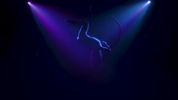 Elements of Twine and Balancing Performed By a Female Aerial Acrobat on an Air Ring. Silhouettes in