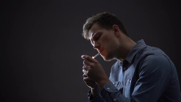 Depressed Man Smoking Isolated on Dark Background, Thinking About Life Problems