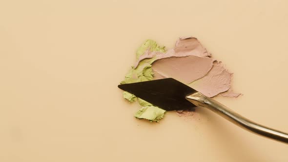 Mixing Green Powder with Foundation on Beige Background