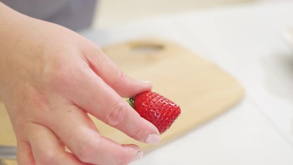 Strawberries are Cut Into Pieces on a Wooden Cutting Board to Decorate Desserts