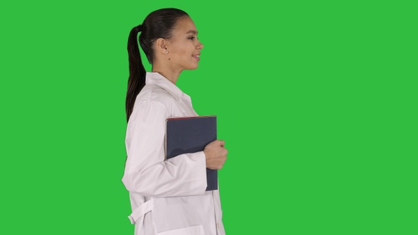 Happy smiling female doctor walking holding notebooks