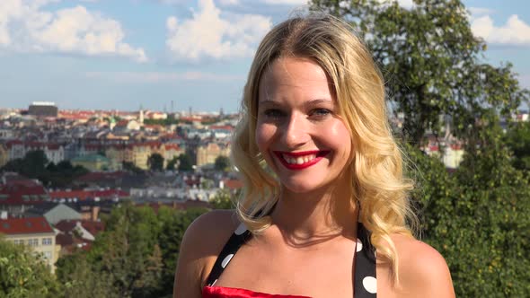 A Young Woman in a Retro Dress Smiles at the Camera - the Cityscape of Prague, Czech Republic