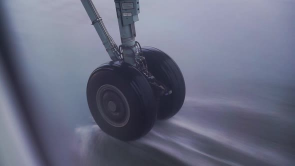 Airplane landing gear taxiing the runway in heavy rain