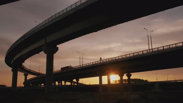 Container semi truck with cargo trailer driving on road bridge carrying goods at sunset or sunrise