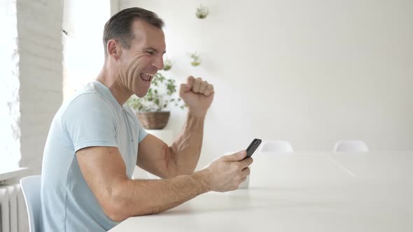 Cheering Man Using Smartphone Profit