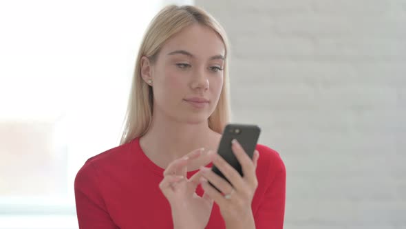 Upset Young Blonde Woman Reacting to Loss on Smartphone