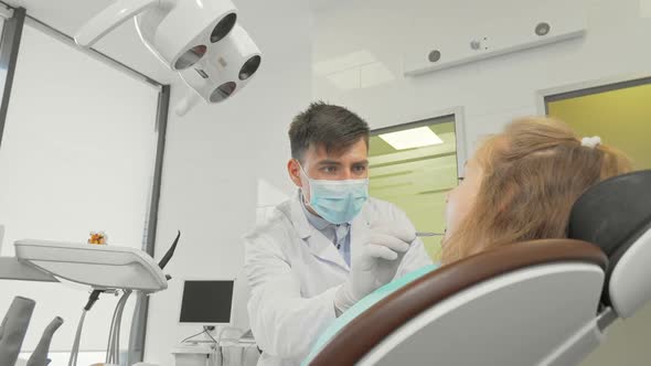 Male Dentist Working at His Clinic Checking Teeth of a Little Girl