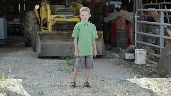 Slow motion of boy with cleft lip standing in front of tractor.