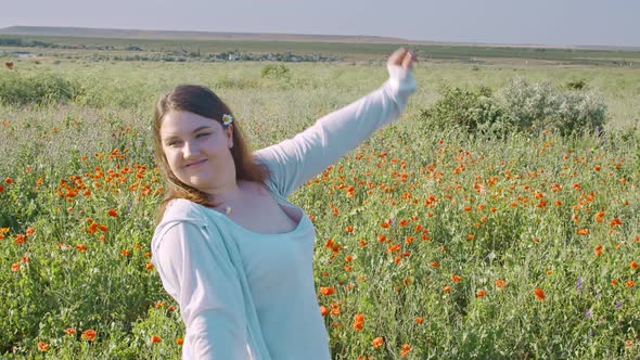 A Young Fat Pretty Woman on the Background of a Field of Wild Poppies with Daisies in Her Hair Moves