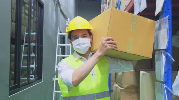 Asian male worker wear mask work during covid pandemic in store warehouse shipping industrial.