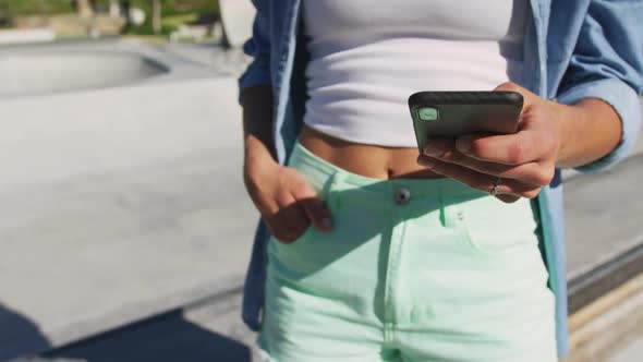 Mid section of caucasian woman using smartphone on sunny day