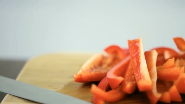 Slicing red bell pepper on a wood cutting board.