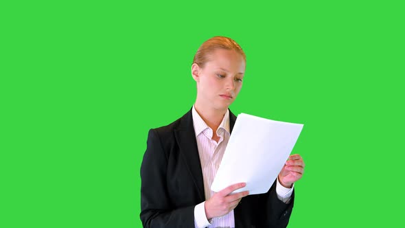 Young Business Woman Looking Through Documents While Walking on a Green Screen Chroma Key