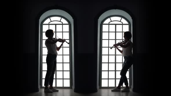 Girl Plays the Violin in the Evening Against the Background of a Window. Silhouette