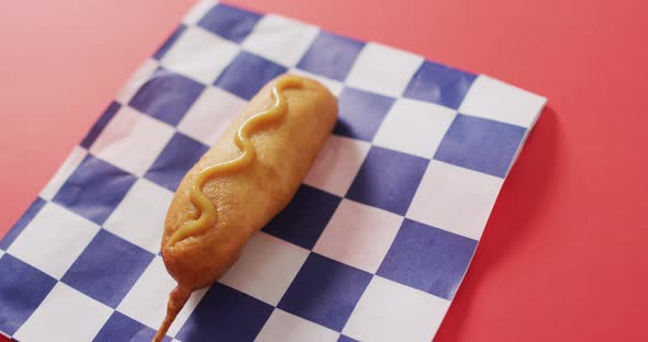 Video of corn dog with mustard on a red surface