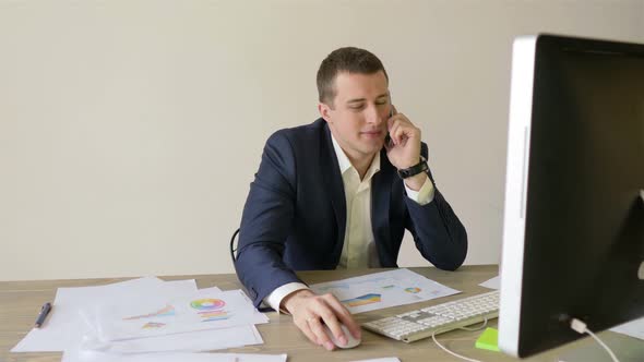 businessman working at the computer in the office and talking on the phone