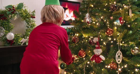 Cute Child Boy Decorates Christmas Tree at Home Preparing for Winter Holidays