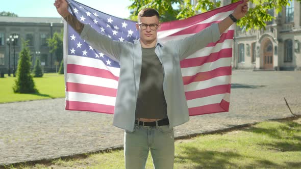 Confident Young Man Spreading Hands Holding American Flag. Portrait of Handsome Intelligent