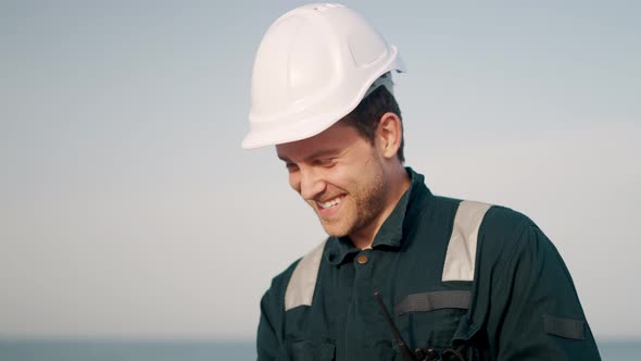 Young Smiling Sailor Man Standing on Deck of Vessel or Ship and Talking with Family Online on Laptop