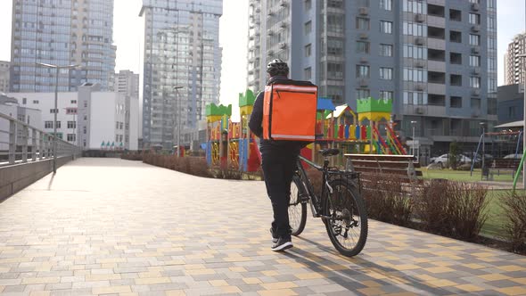 Food Courier Walking with Thermal Bag and Bike