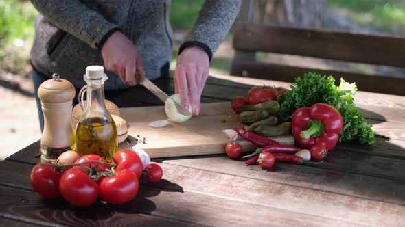 Woman Cuts Onion Making Vegetable Salad Outdoors