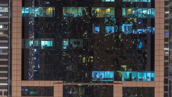 Windows of the Multistorey Building of Glass and Steel Lighting Inside and Moving People Within