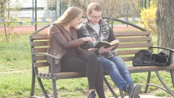 People Sitting on Bench in the Park in Summer and Reading a Book