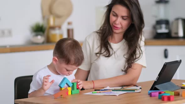 Kid Boy and Mother Playing Educational Toys at Table at Home