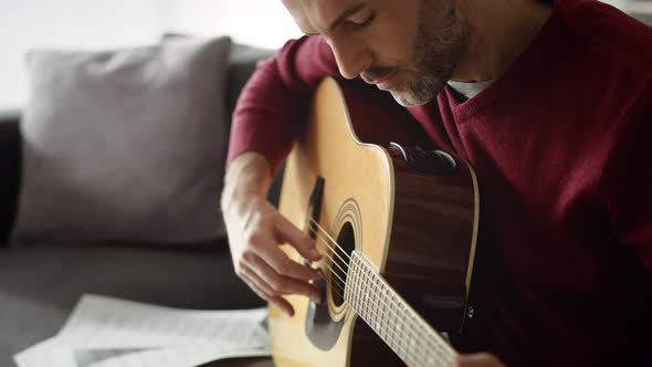 Tilt up video of man playing acoustic guitar at home. Shot with RED helium camera in 8K.