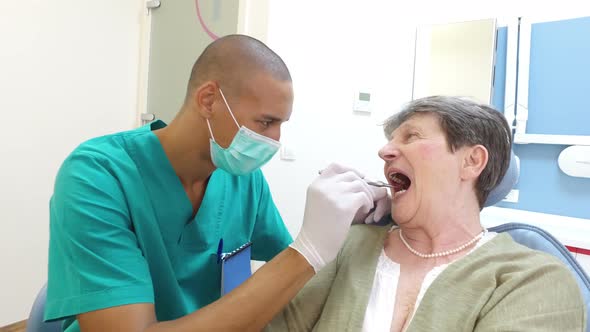 Dental assistant examining elderly female patient