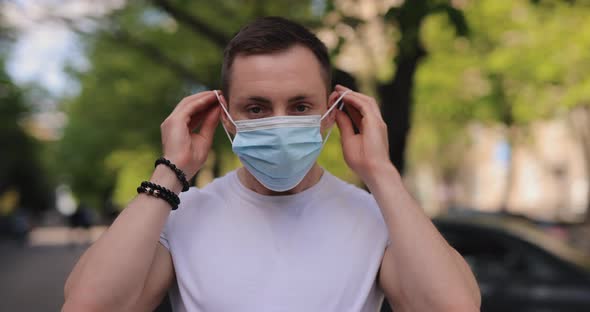 Man Putting on Surgical Mask in a City