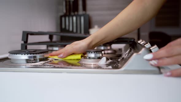 Hand cleaning stove. Close up of female hand cleaning the gas stove in kitchen