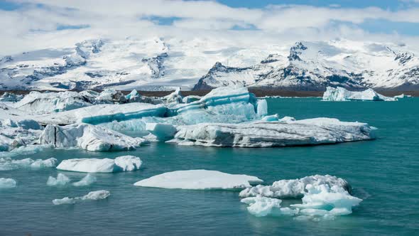 Small Icebergs floating on Blue lagoon, Jokulsarlon, sunny day, telephoto shot, time lapse