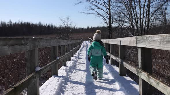 little girl walking down winter nature path slomo zoomed follow