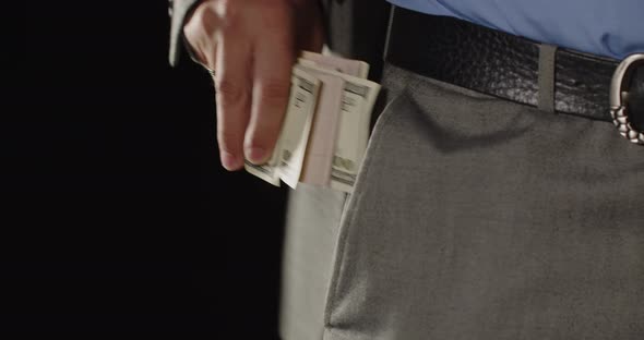 Male Hand Puts Dollar Bills In His Pocket