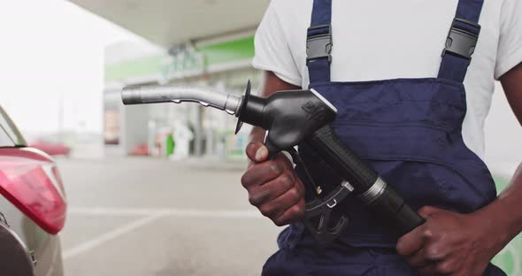 A Black African Refueling Worker Holds A Gun To Refuel A Car