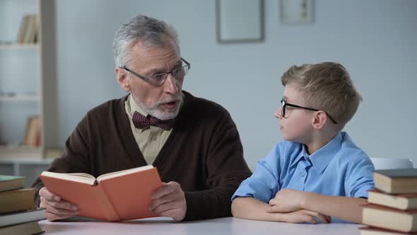 Sad Boy Wants to Play Instead of Boring Pastime With Grandfather Reading Book