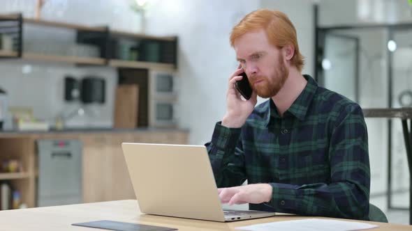 Beard Redhead Man with Laptop Talking on Smartphone 