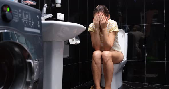 Upset Woman Crying While Sitting on the Toilet