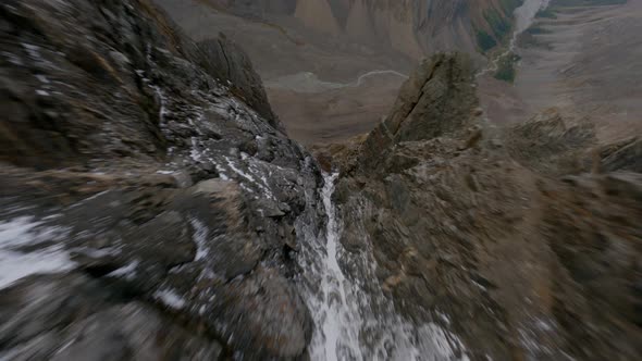 FPV Sports Drone Shot Dive From Epic Snow Summit Texture Along Narrow Snowy Couloir Sheer Cliff