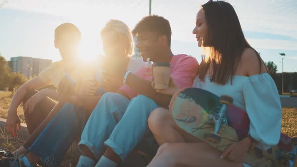 Happy Smiling Teenage Friends Laughing Outside at Something in Smartphone or Mobile Phone