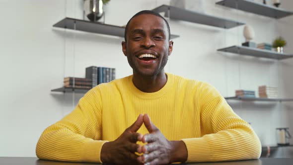 Young smiling man communicating by videoconference at home