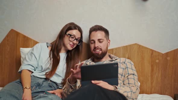 Young couple watching video on tablet in hotel room