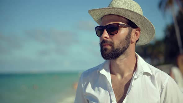 Man Walking On Tropical Beach. Guy Relaxing On Caribbean Sea Beach. Tanned Man In Hat.