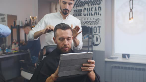 Businessman Using Tablet Visiting Barber Shop for Haircut