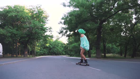 Beautiful Young Girl with Green Hair Riding on Longboard During Sunset Tracking Shot