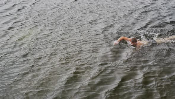 Caucasian man having a good time on a trip to the mountains, wearing swimming trunks and swimming in