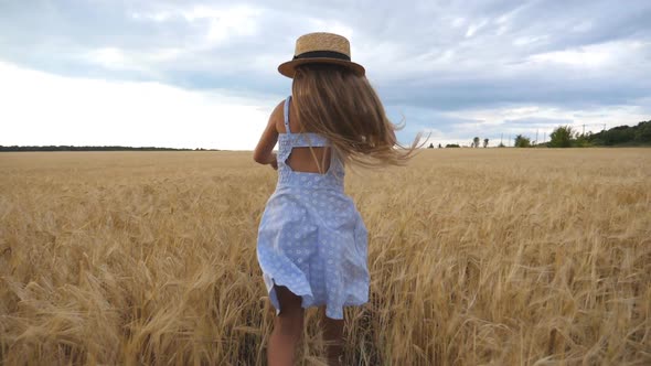 Beautiful Girl with Long Blonde Hair Running Through Wheat Field Turning To Camera and Smiling